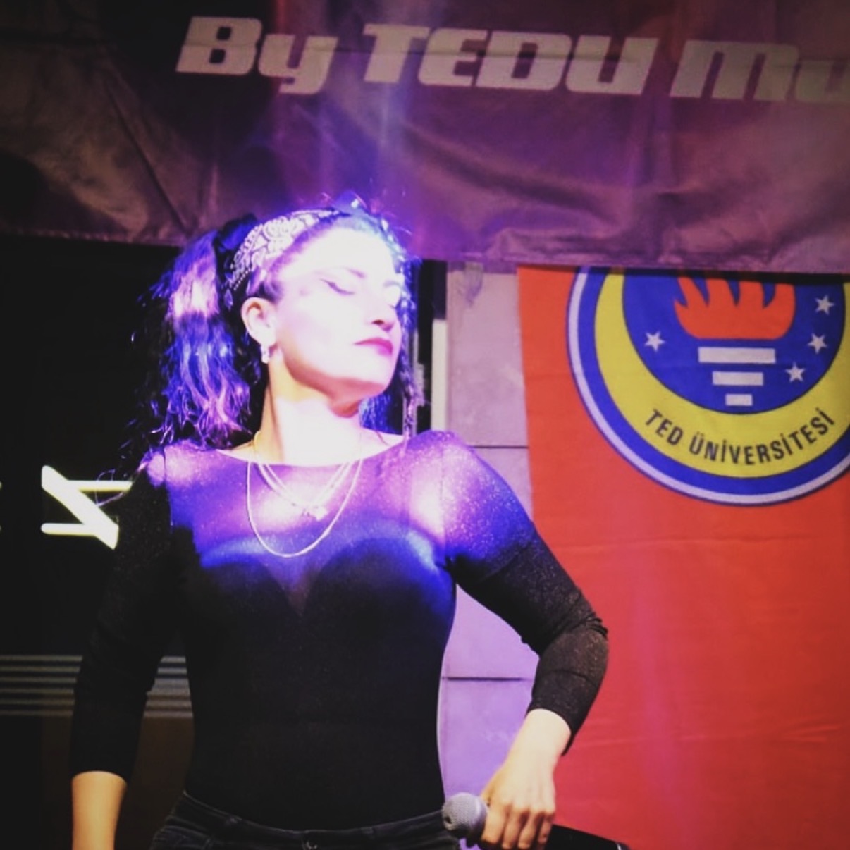 Beste Kırmacı TED Üniversitesi bayrağı önünde TEDU VOICE sahnesinde